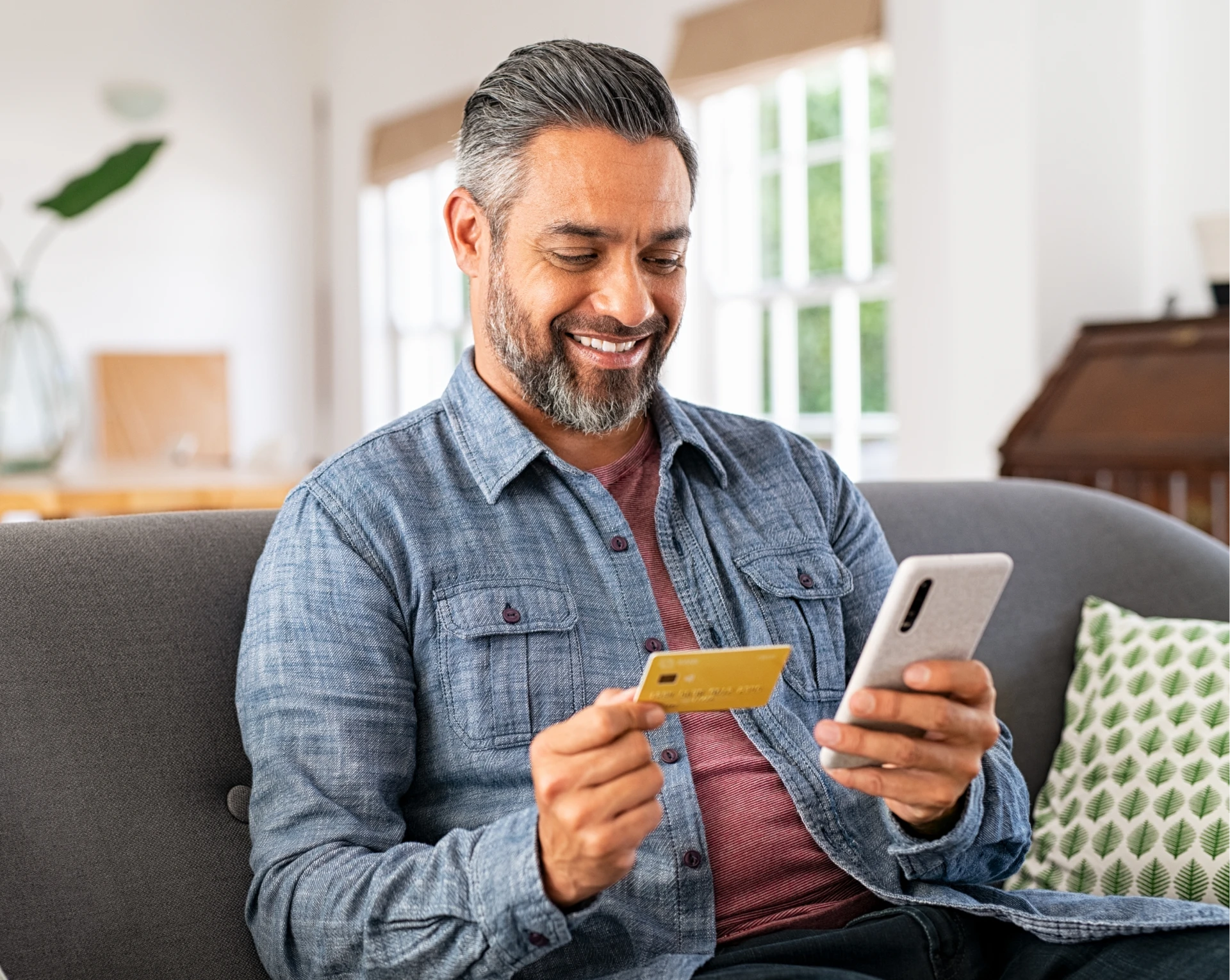 Smiling man using phone and credit card